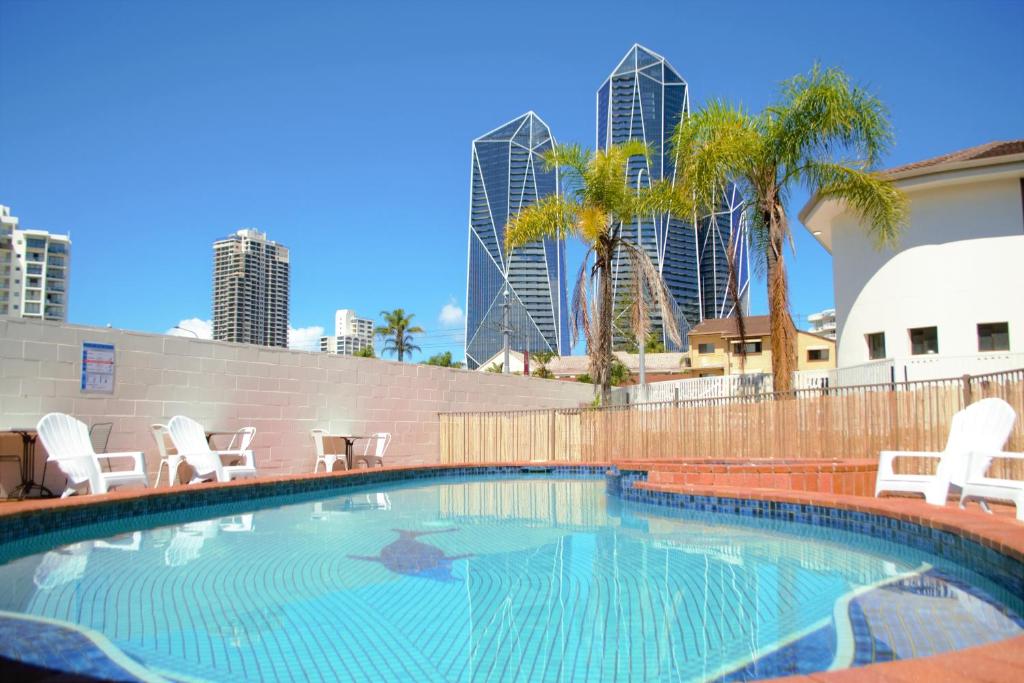 a swimming pool with chairs and palm trees and buildings at Gold Coast Inn in Gold Coast