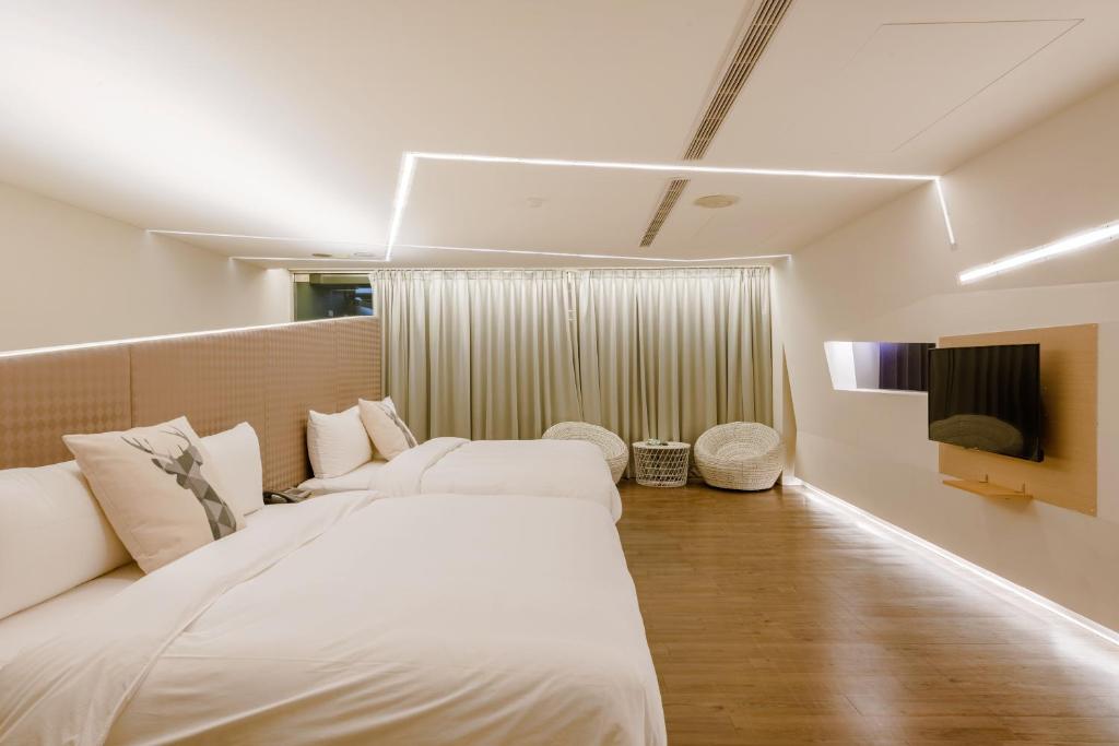 a bedroom with a large white bed and a television at Ya Nold Hot Spring Hotel in Jiaoxi