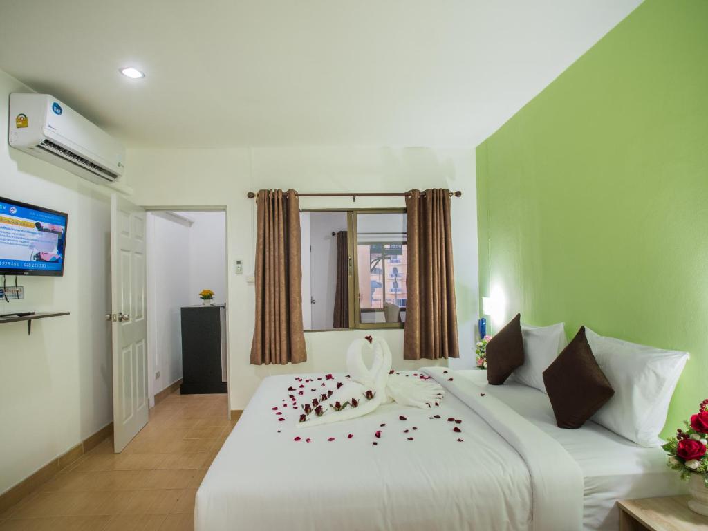 Un dormitorio con una gran cama blanca con flores. en TJ Guesthouse, en Pattaya central