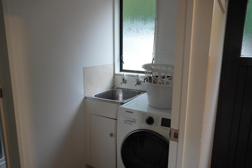 a small kitchen with a sink and a washing machine at Lazy Daze in Wanaka