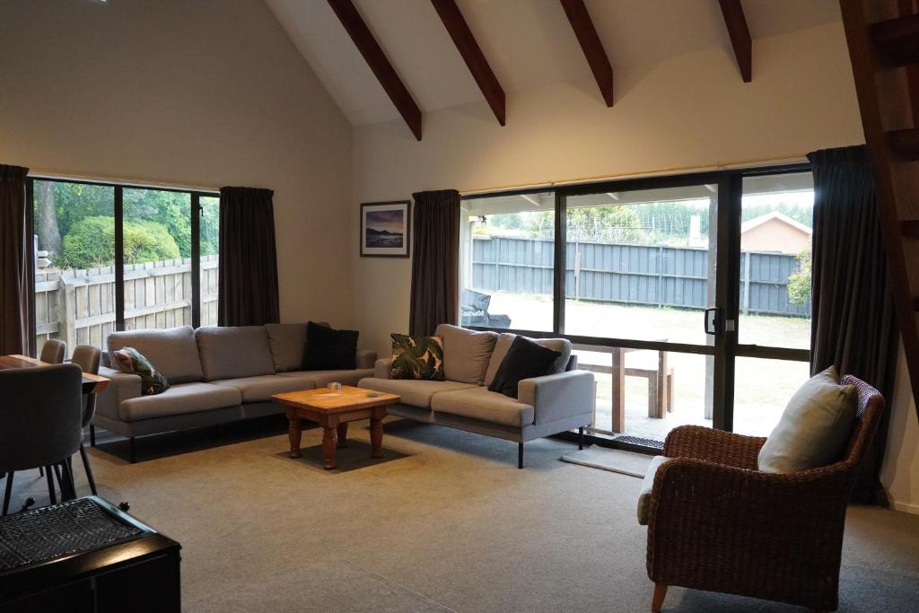 a living room with couches and a table and windows at Lazy Daze in Wanaka
