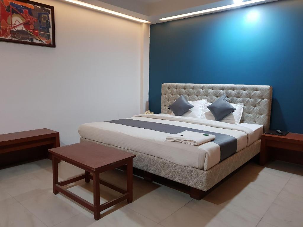um quarto com uma cama com uma parede azul em Pleasure Inn em Bhopal