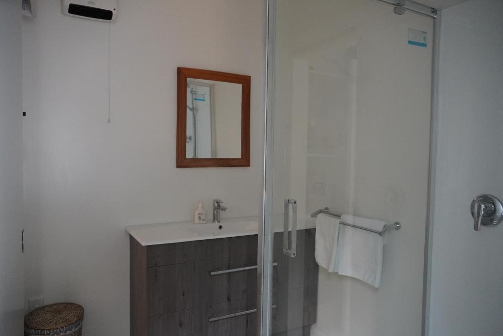 a bathroom with a sink and a shower with a mirror at Lazy Daze in Wanaka