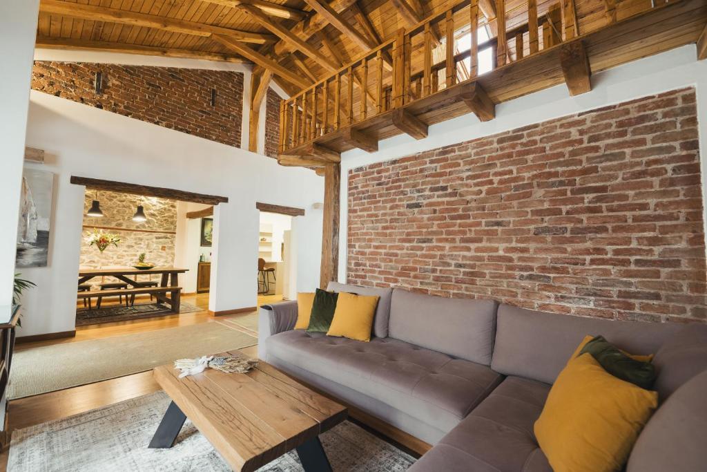 a living room with a couch and a brick wall at Four Season Maison in Kavála