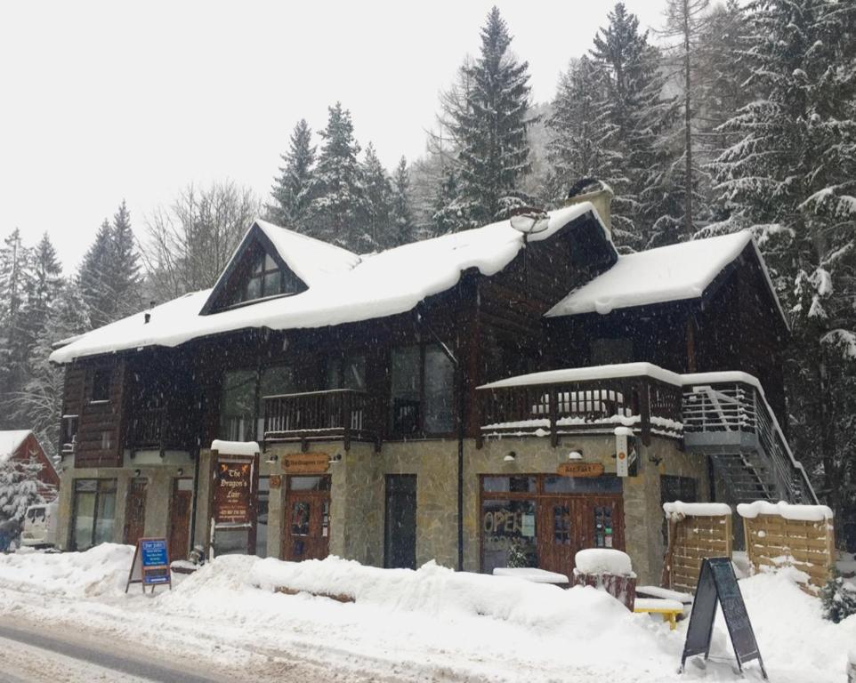 a building with snow on the roof of it at The Dragon's Lair Chalet in Belá