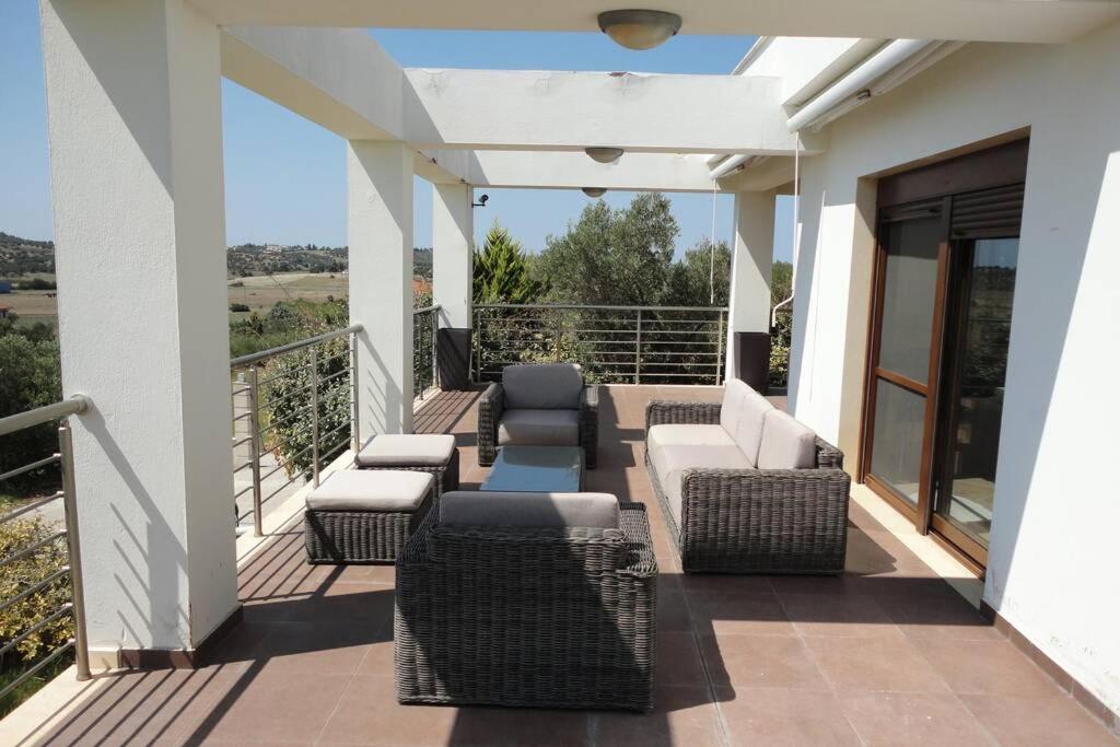 eine Terrasse mit Sofas und Stühlen auf dem Balkon in der Unterkunft Villa Maria Ποσείδι Χαλκιδικής Σπίτι με θέα in Posidi