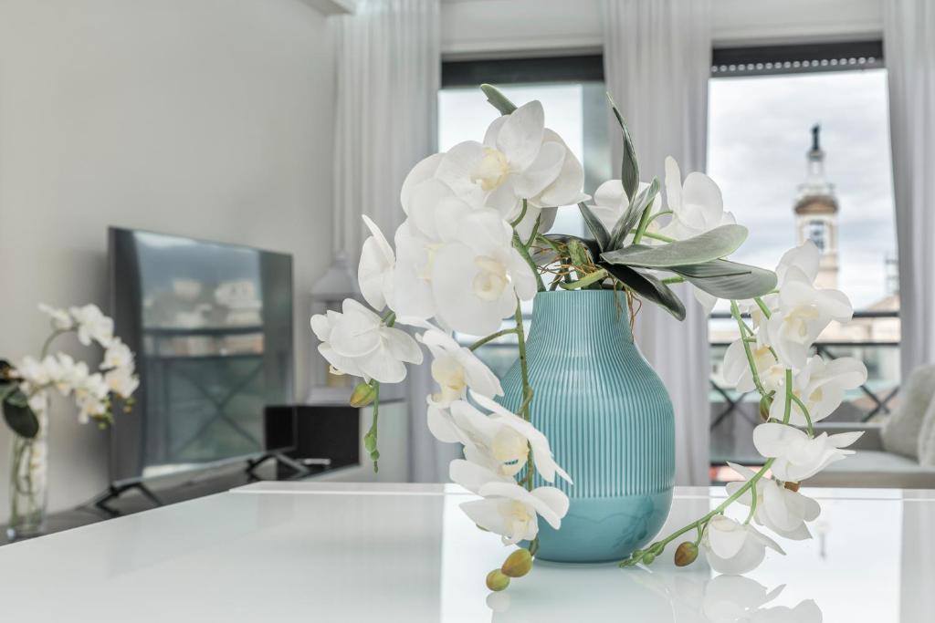 Guest House Foligno Porta Romana في فولينيو: مزهرية زرقاء مع الزهور البيضاء على الطاولة