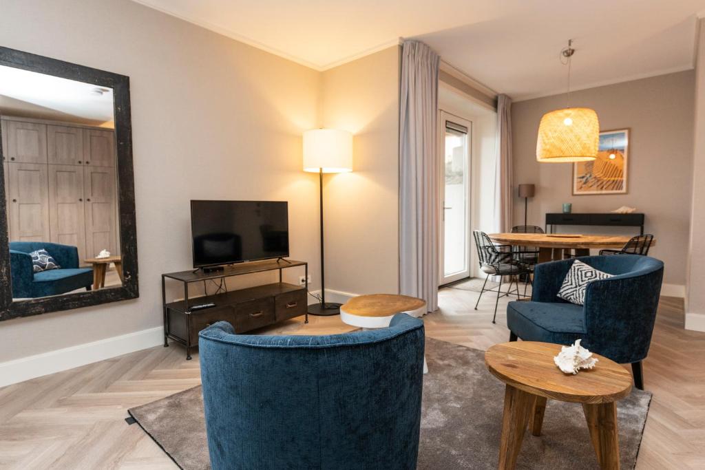 een woonkamer met blauwe stoelen en een televisie bij Hampton home B&B suites in De Koog