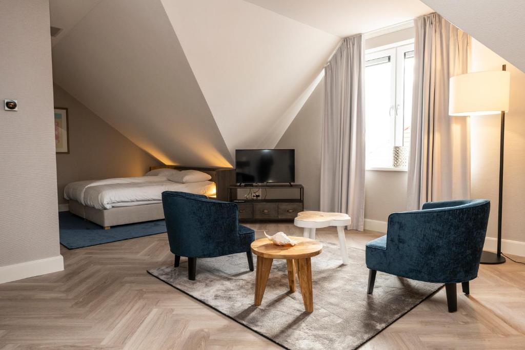 een kamer met een bed en twee stoelen en een tafel bij Hampton home B&B suites in De Koog