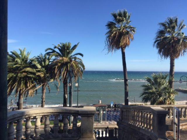 a view of a beach with palm trees and the ocean at Petit avec classe Sanremo in Sanremo