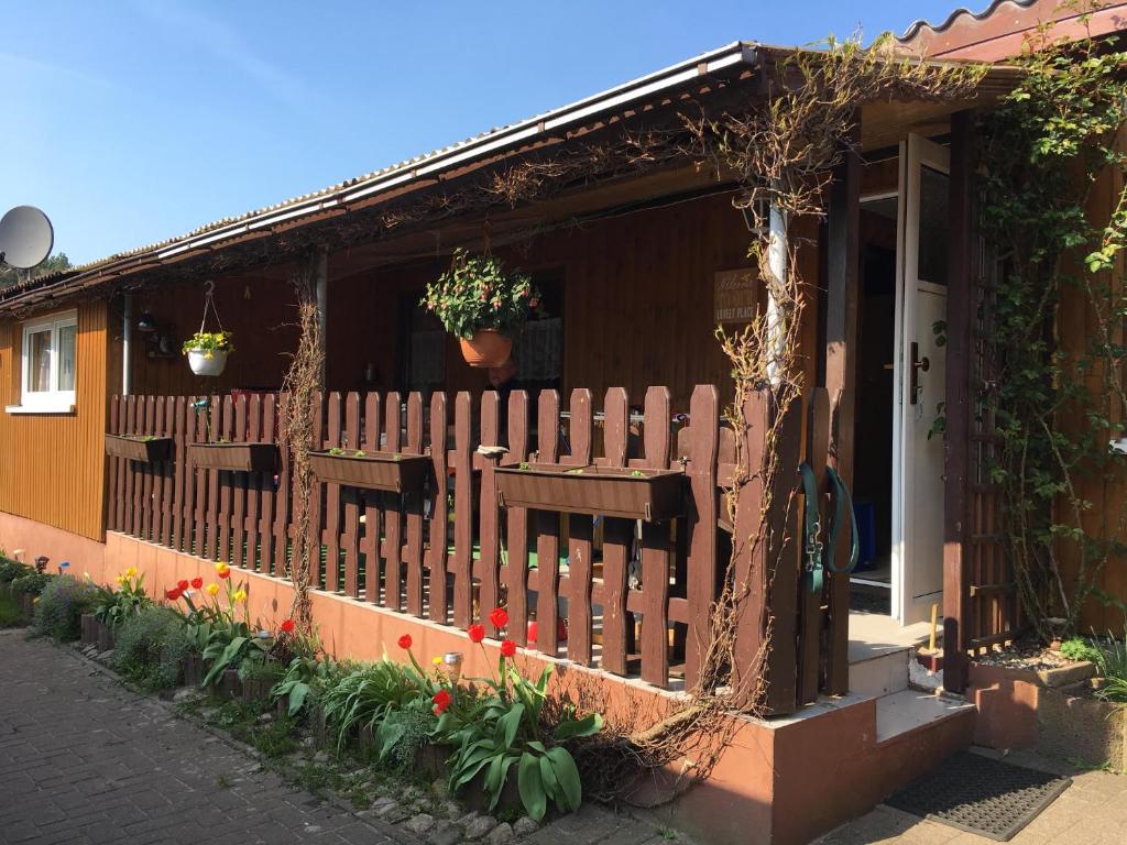 a house with a wooden fence and flowers at Ferienbungalow Karnitz/Rügen in Karnitz