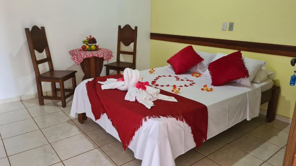 a bedroom with a large bed with a red and white blanket at POUSADA SERRA DA CANASTRA in Delfinópolis