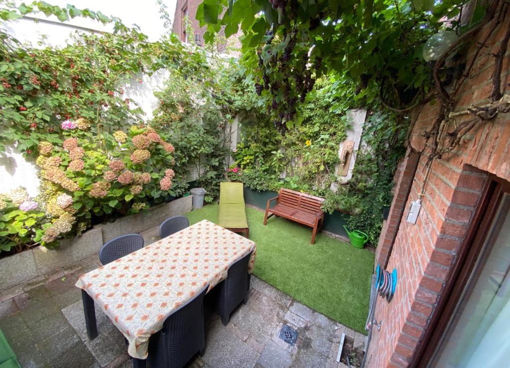 een patio met een tafel, een bank en planten bij Stadswoning Roermond in Roermond