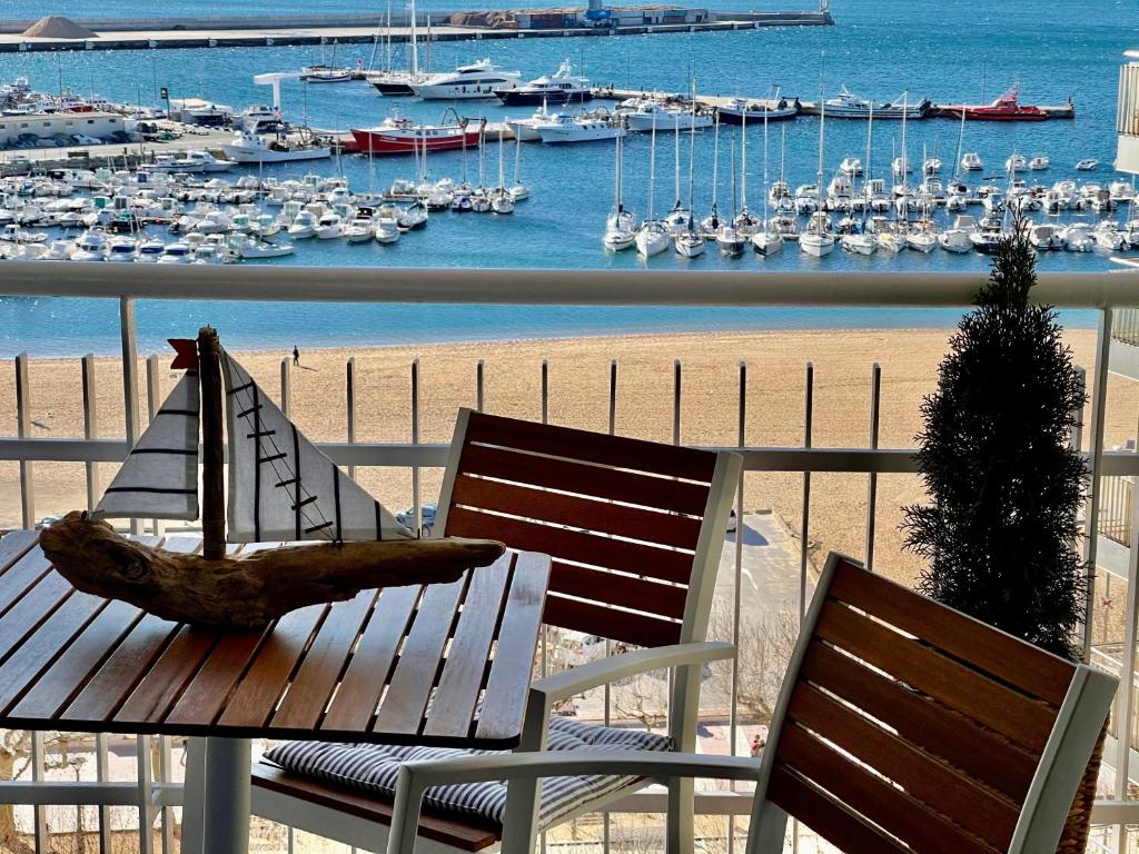 eine Holzbank auf einem Balkon mit Blick auf den Yachthafen in der Unterkunft APARTMENT PANORAMIC VIEW PALAMÓS in Palamós