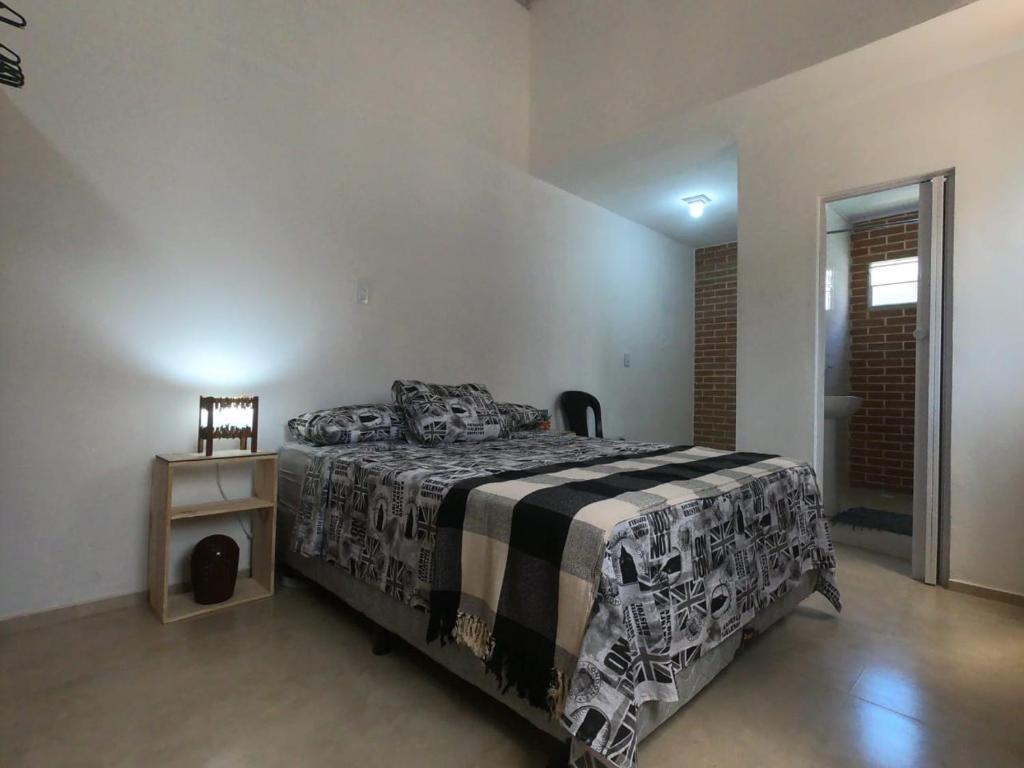 una camera con un letto con una coperta bianca e nera di Paul's kitchenettes da praia & Nemo dive, centro de mergulho a Santa Cruz Cabrália