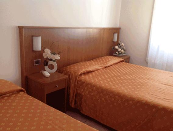 una camera d'albergo con due letti con lenzuola arancioni di Hotel Aquilia a Laigueglia