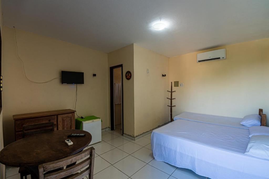 a bedroom with a bed and a table and a television at Pousada Cruzeiro dos Anjos in Tabatinga