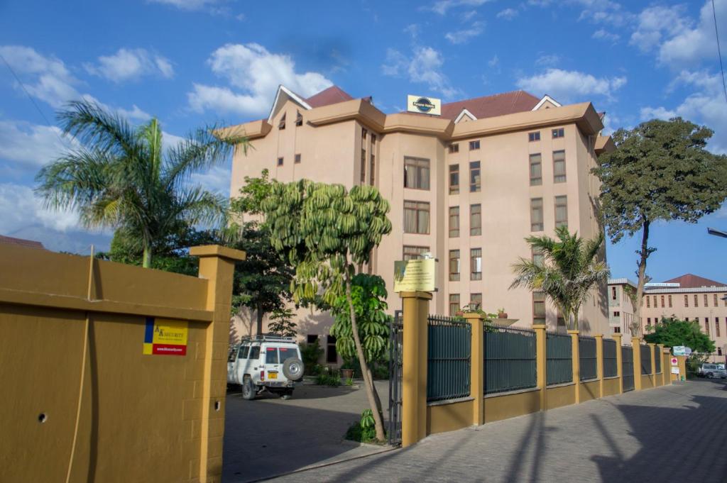 un grand bâtiment avec une clôture devant lui dans l'établissement Panone Hotels - Sakina, à Arusha