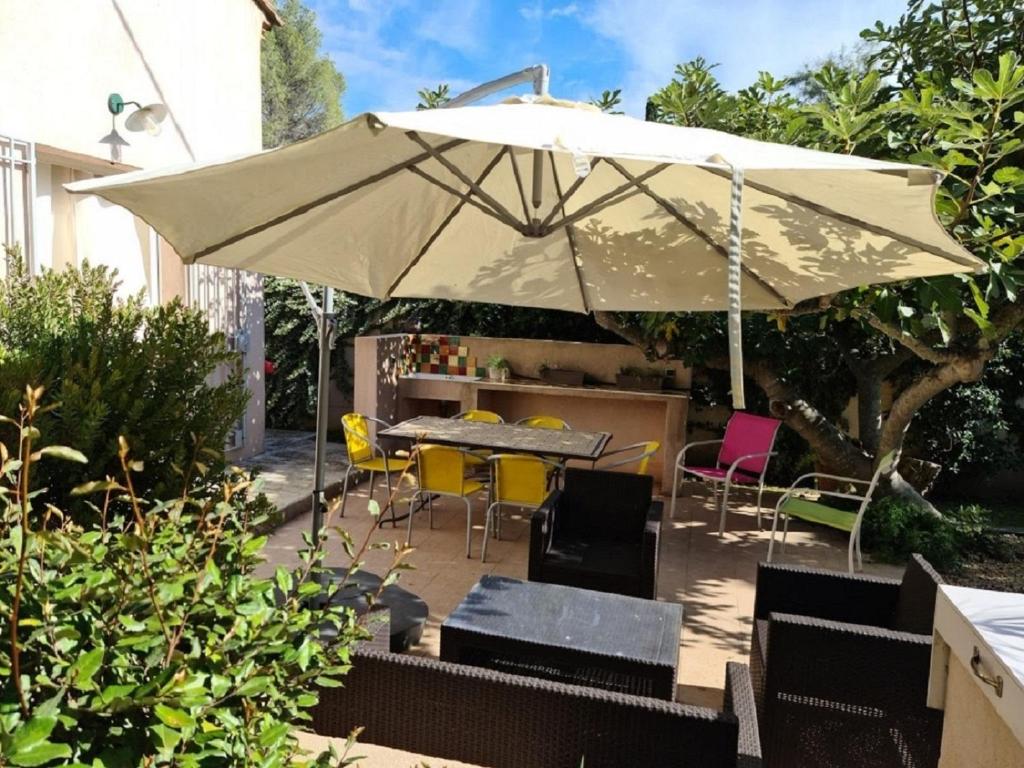 un patio con sombrilla, mesa y sillas en Le Hameau de la Nicolinière en Bormes-les-Mimosas