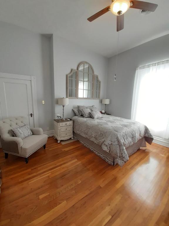 a bedroom with a bed and a chair and a ceiling fan at Queens Chamber w King Heavenly Bed at Nottingham Place in Wise in Wise