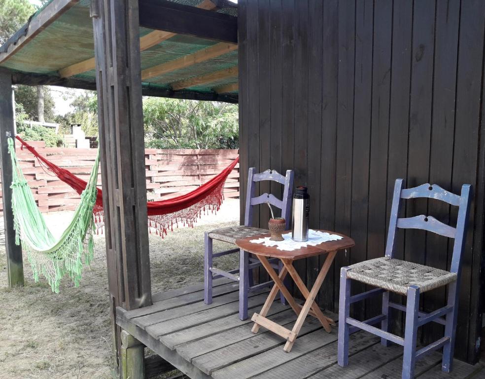 una mesa y dos sillas sentadas en un porche en Cabaña La Genio, en Punta del Diablo