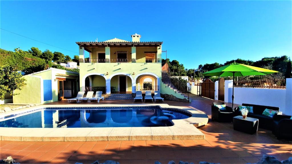 a villa with a swimming pool in front of a house at Villa Costa in Moraira