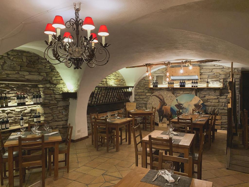 restauracja z drewnianymi stołami i kamienną ścianą w obiekcie Locanda Allevè Hotel Ristorante w mieście Pragelato