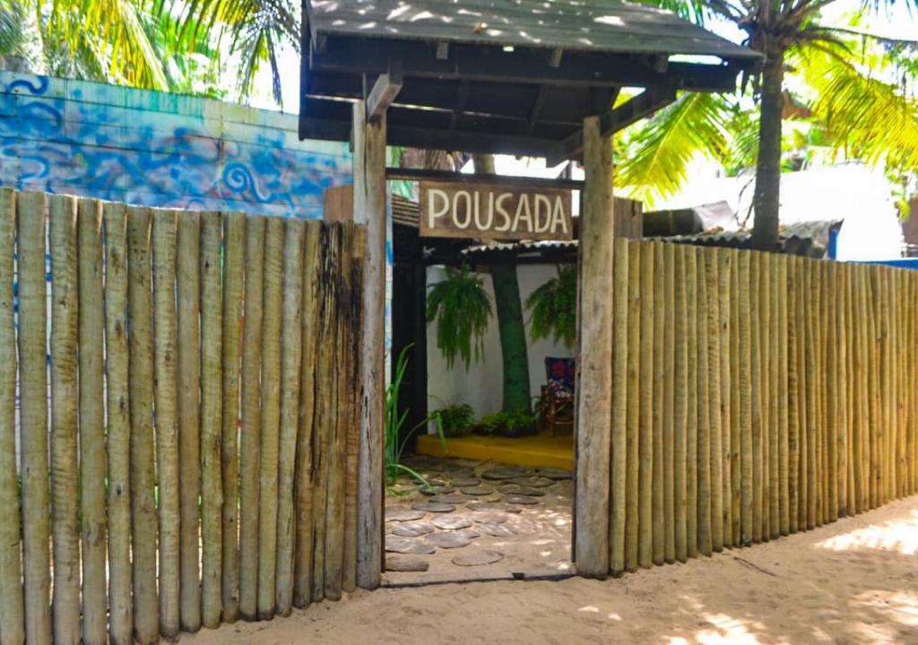 uma cerca de madeira em frente a um edifício com uma placa em Pousada da Elma - Praia em Trancoso