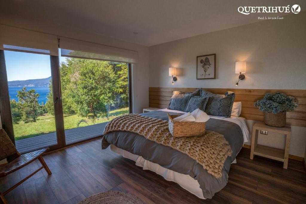 a bedroom with a large bed and a large window at QUETRIHUE in Puerto Varas