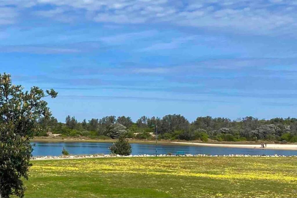 a view of a lake with a grass field and trees at Driftwood Townhouse - Waterfront-Central Location in Lakes Entrance