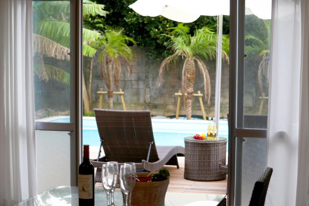 un patio con una mesa con copas de vino y una piscina en Pool Villa Sesoko jima, en Motobu