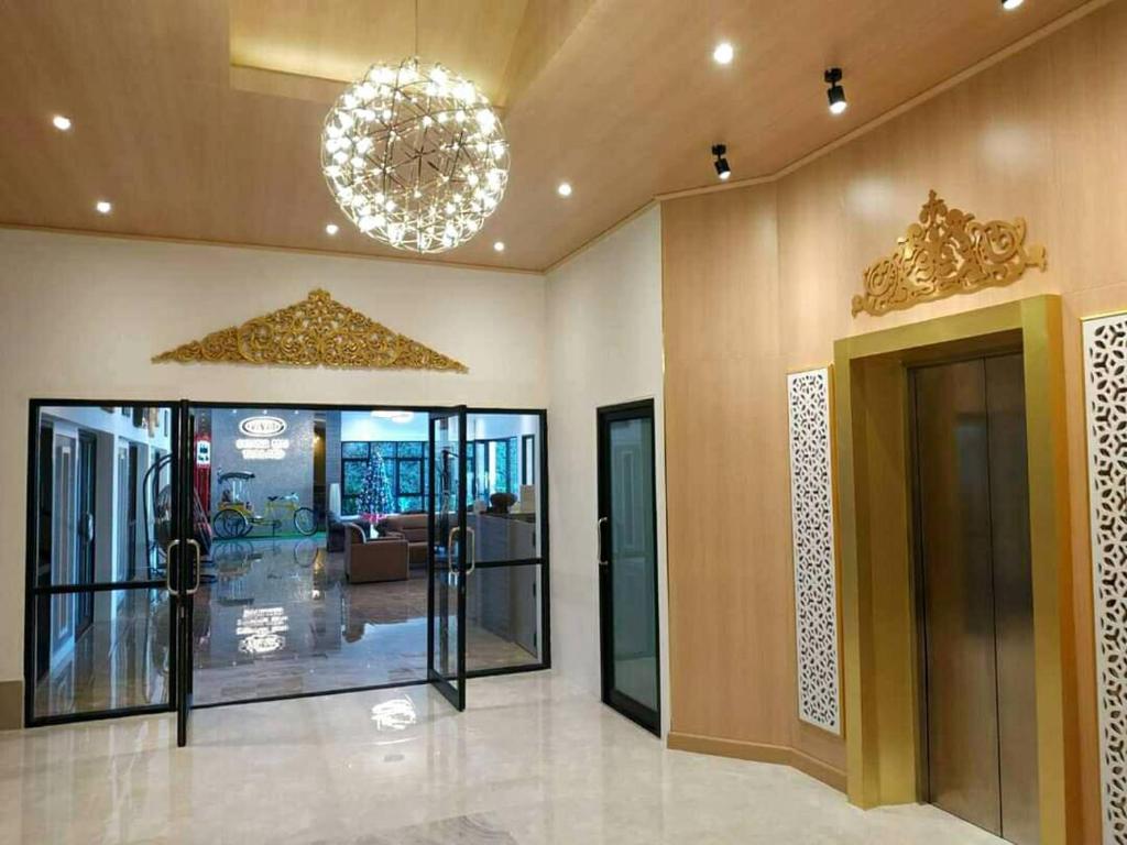 An elevator lobby with gold decorative detailing, glass entrance doors and a spherical chandelier.