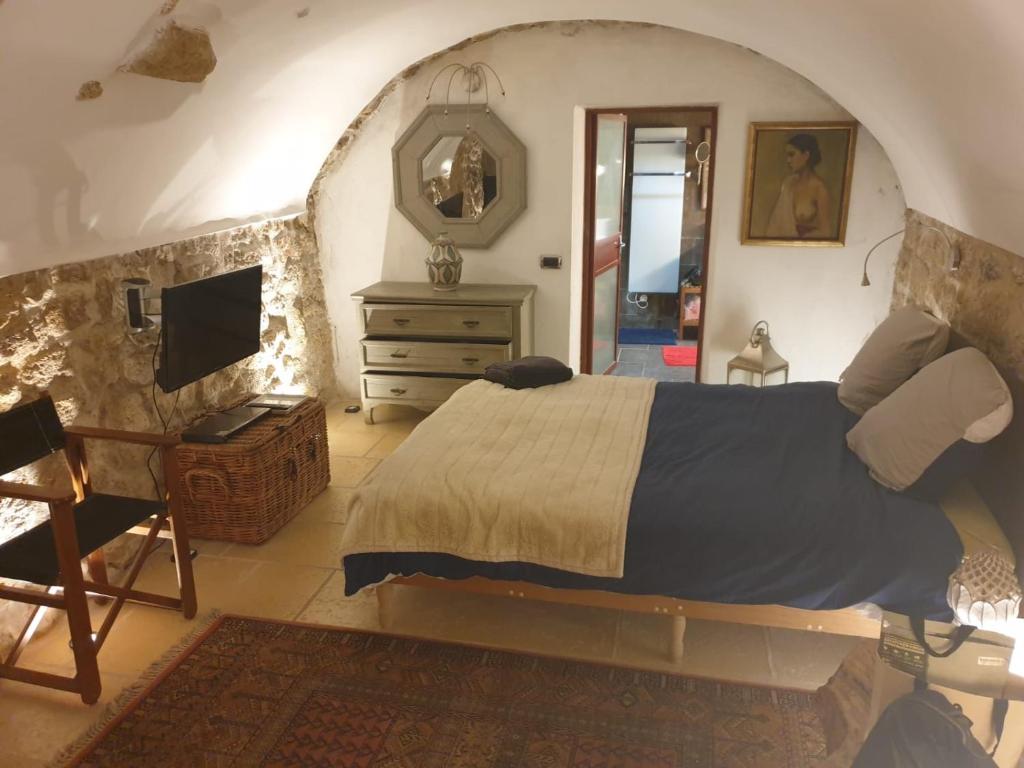 a bedroom with a bed and a dresser and a television at la villageoise, chambre troglodyte pitoresque au cœur du village in Rognes