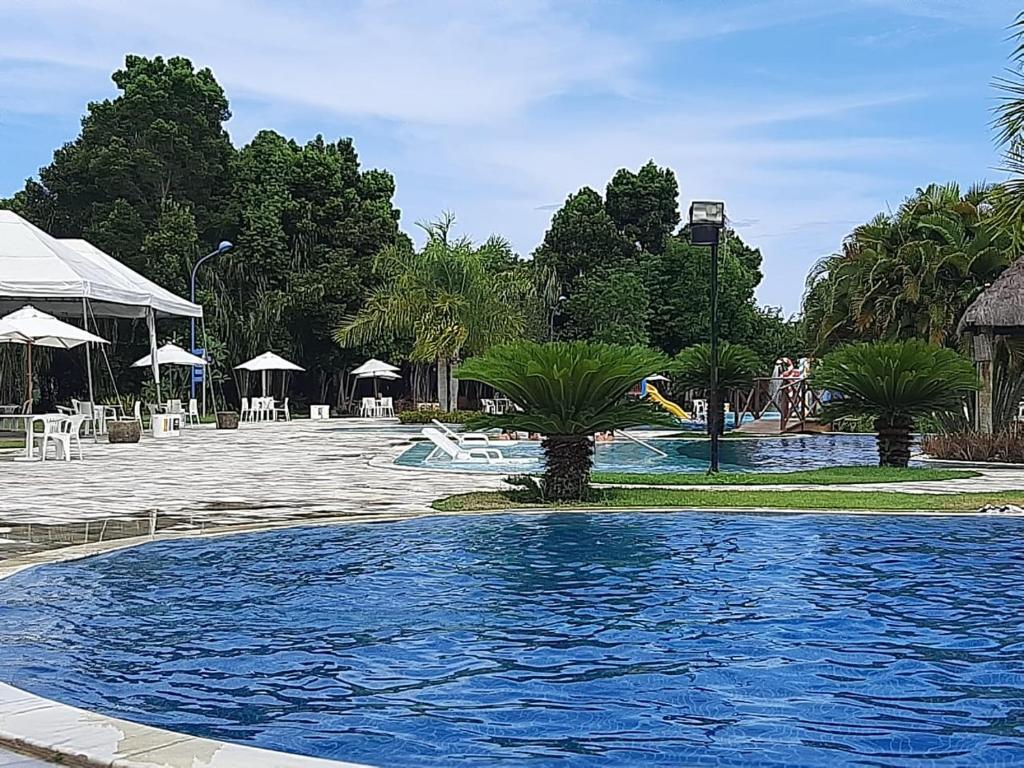 uma piscina num resort com palmeiras em Residencial Iloa na Barra de São Miguel
