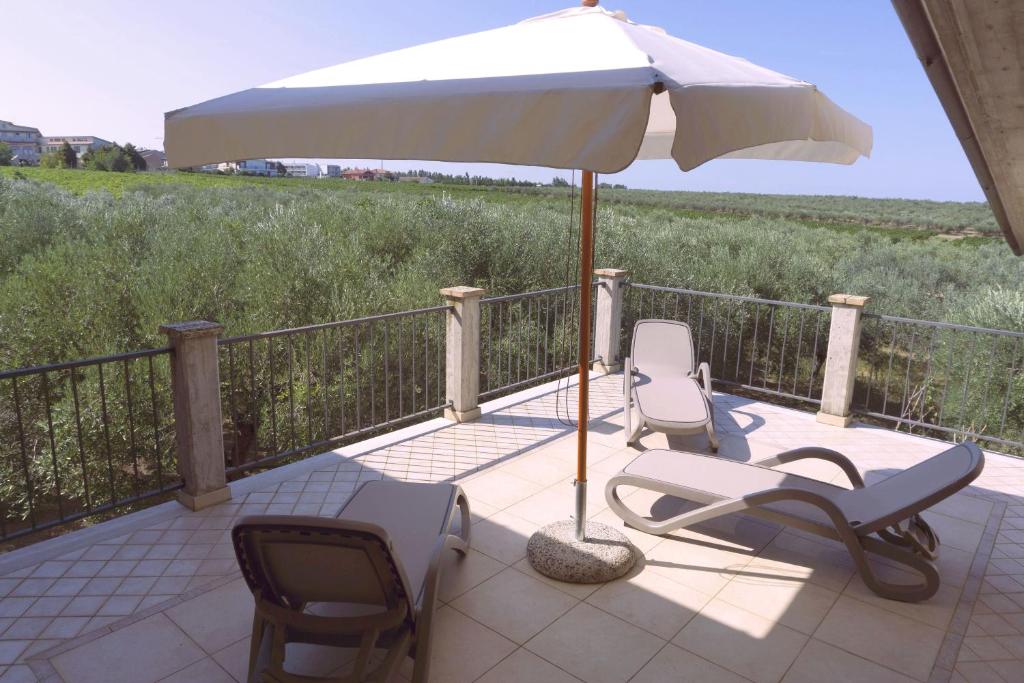 a patio with two chairs and an umbrella at B&B Tra Gli Ulivi in Vasto
