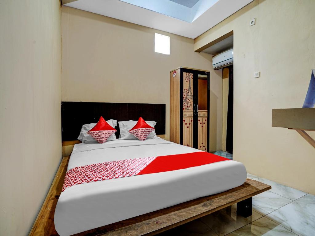 - une chambre avec un grand lit et des oreillers rouges dans l'établissement OYO Capital O 90081 Pondok Sabaraya 2 Syariah, à Cikampek