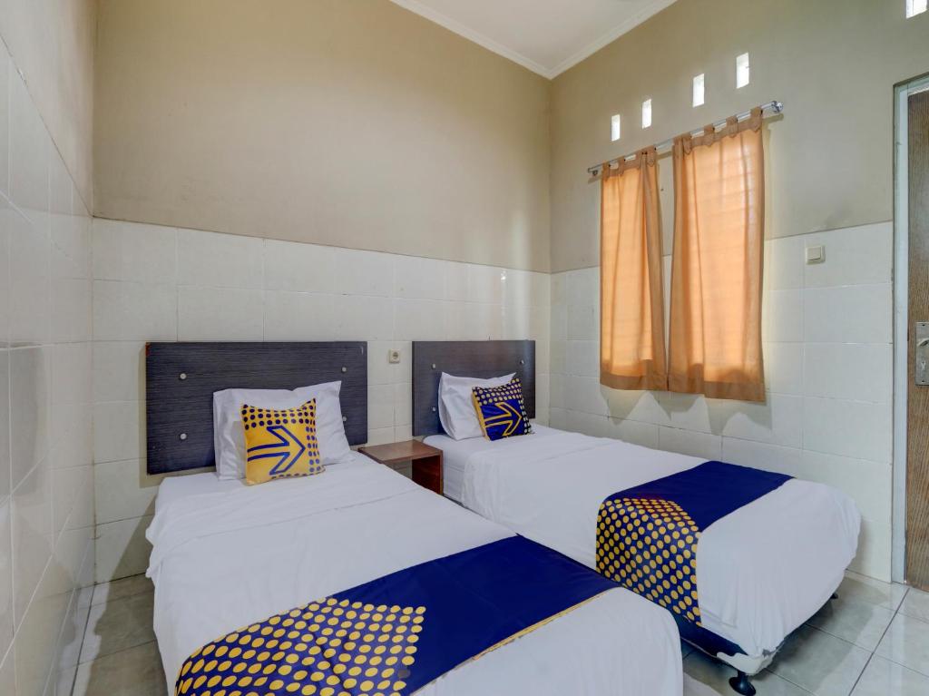 2 Betten in einem kleinen Zimmer mit Fenster in der Unterkunft OYO Life 90159 Puri Asoka Guest House in Tuntang