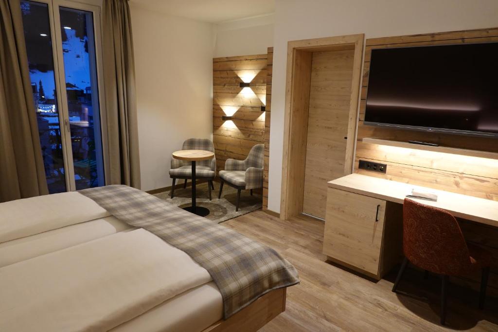 a hotel room with a bed and a flat screen tv at Hotel Schweizerhof in Engelberg
