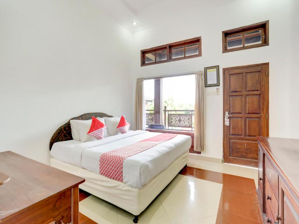 a bedroom with a large bed and a window at SUPER OYO 3261 Hotel Ratu in Denpasar