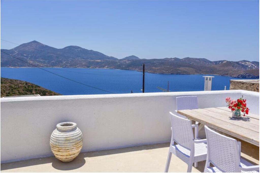 a table and chairs and a vase on a balcony at Traditional Cycladic House in Tripití