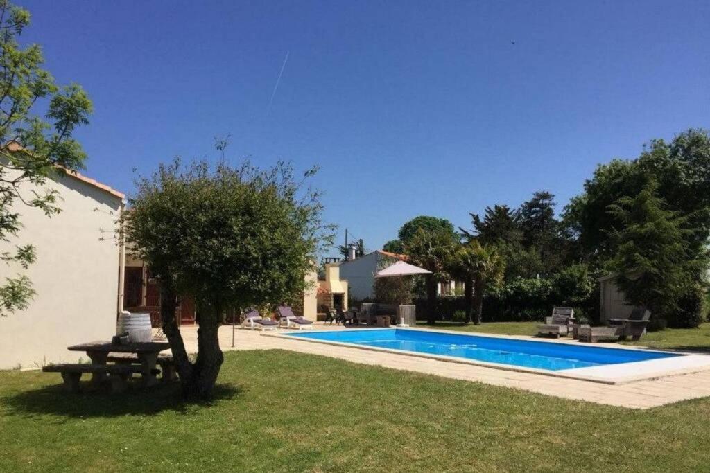 une cour avec une piscine et une maison dans l'établissement La Villa du Payré, proche mer et piscine chauffée, à Jard-sur-Mer