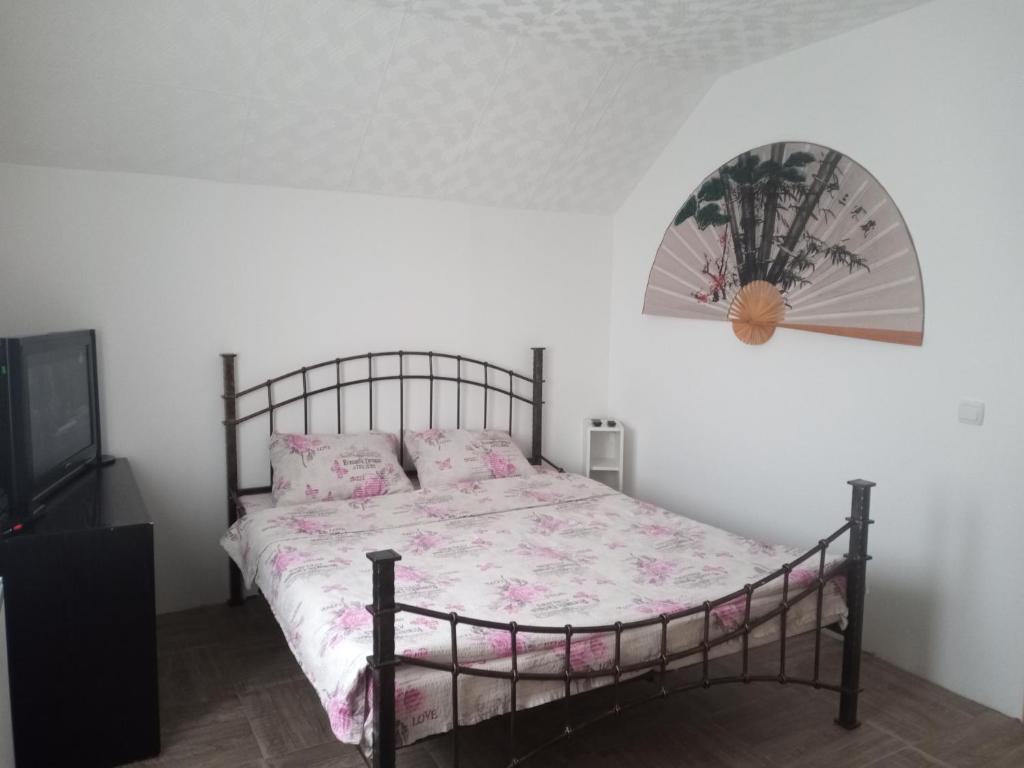 a bedroom with a bed with pink sheets and a fan at Apartman Visnja in Crni Vrh