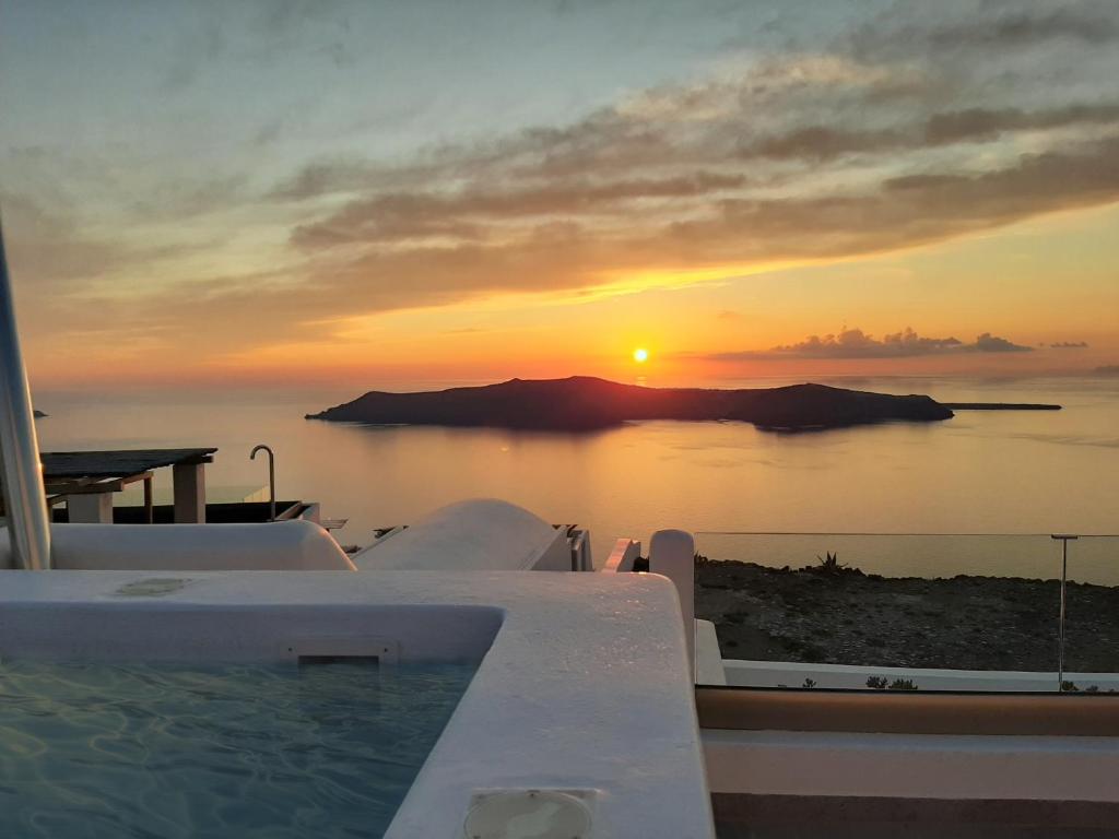 a sunset over the water with a swimming pool at Vitsentzos Suites in Imerovigli