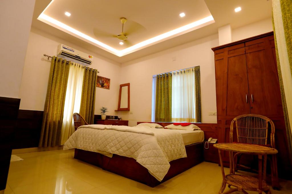 a bedroom with a bed and a cabinet and a chair at SAPPHIRE INN in Nedumbassery