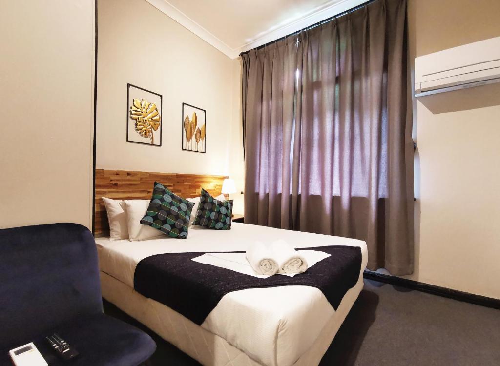 a bedroom with a bed with a chair and a window at Sydney Crecy Hotel in Sydney