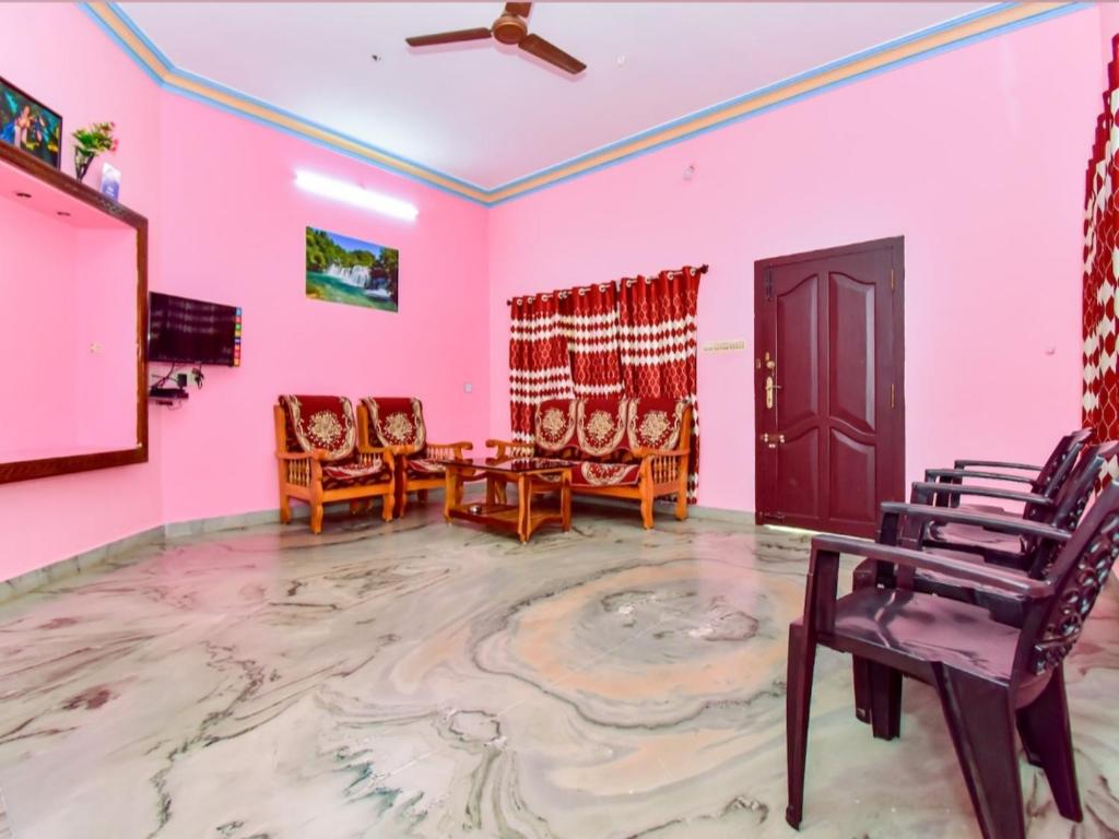 a room with pink walls and chairs and a ceiling fan at Phoenix Holiday Home in Kanyakumari