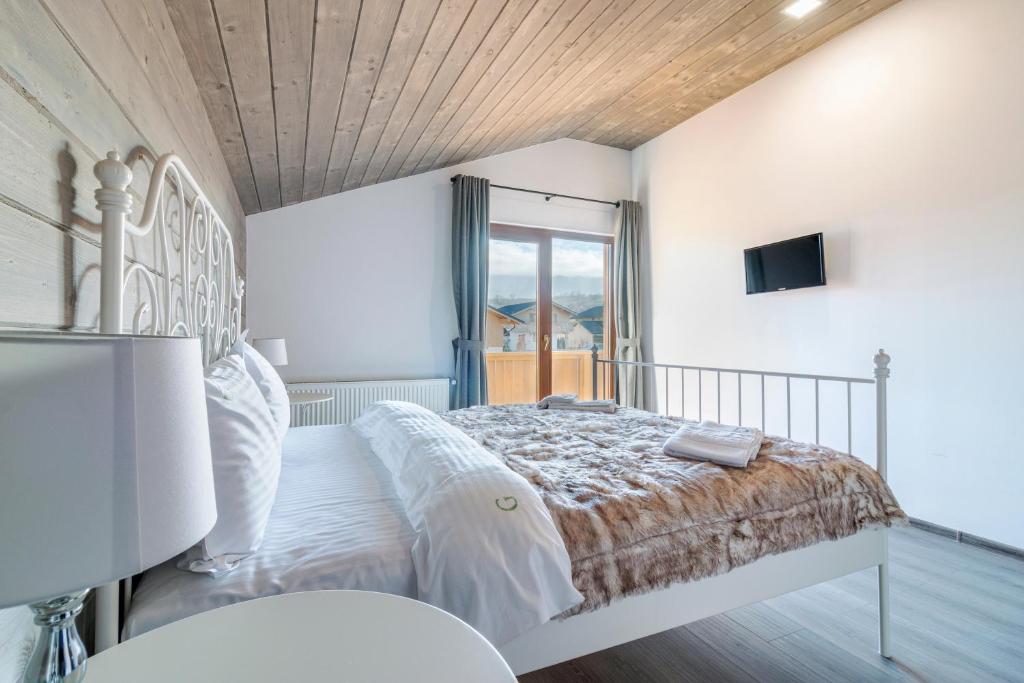 a white bedroom with a bed and a window at Green Resort Bran in Bran