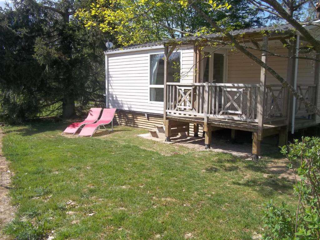 una casa con terraza y un banco rosa en un patio en camping aire du gros pré, en Lesseux