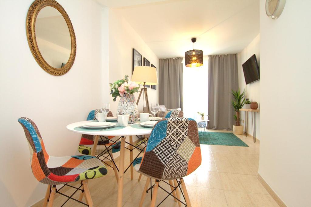 a dining room with a table and chairs and a mirror at Apartamento Mar De L'est 450 m de la playa con piscina in Gandía