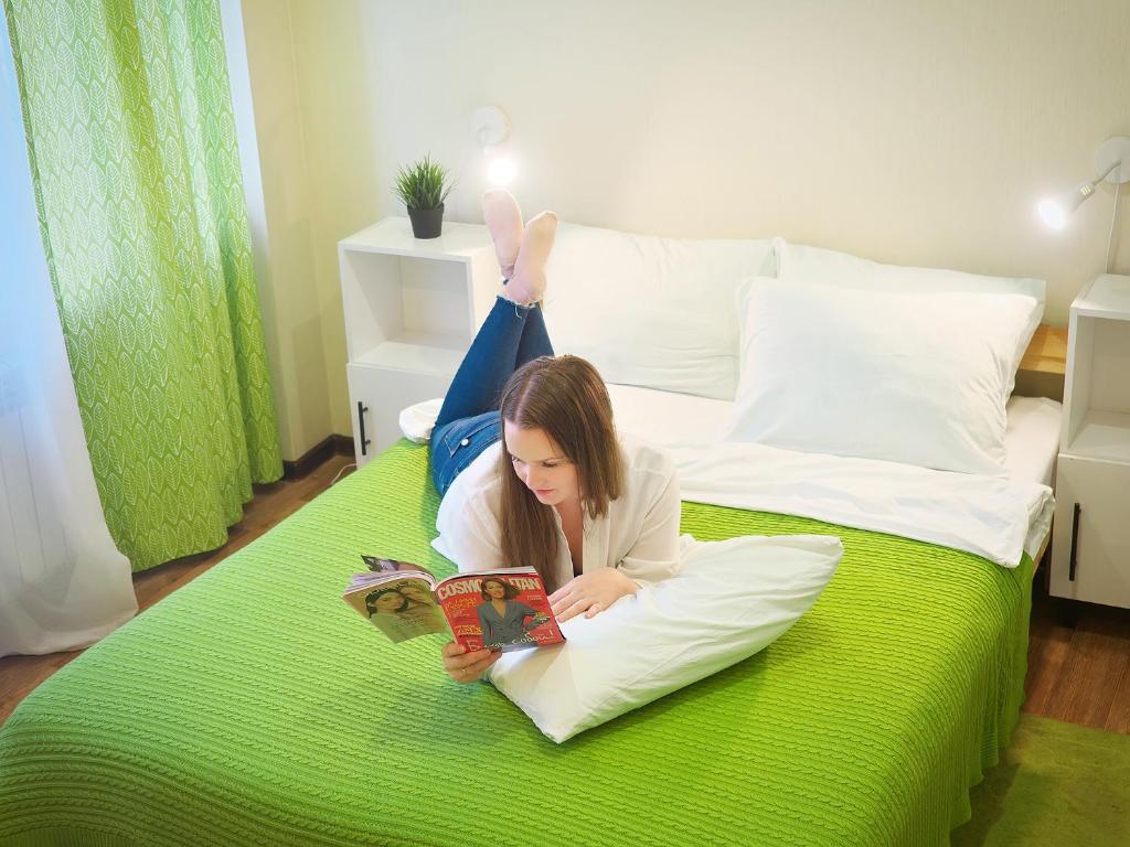 a girl laying on a bed reading a book at Тук Тук Хостел in Yaroslavl